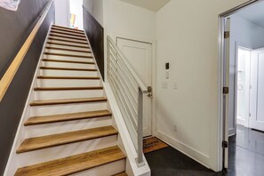 A staircase with wooden steps and white railings leading to a white door with a doormat. - 16 Bed Private Gulch Home with Rooftop (Nashville)