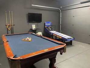 A pool table with balls and cues, a television mounted on the wall, and a hot shot arcade machine. - 16 Bed Private Gulch Home with Rooftop (Nashville)