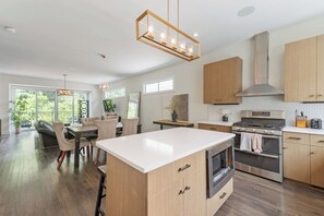 Une cuisine moderne dotée d’un îlot central, d’appareils électroménagers en acier inoxydable et de meubles de rangement en bois.