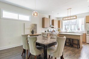 A modern kitchen with a central island, bar stools, and pendant lighting.