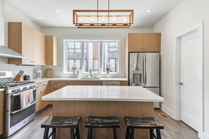 A modern kitchen with a large island, stainless steel appliances, and wooden cabinetry.