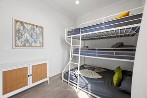 A bunk bed room with a rattan cabinet and a framed picture on the wall.