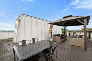 A covered outdoor patio with a table and chairs, a wicker sofa, and a pergola.