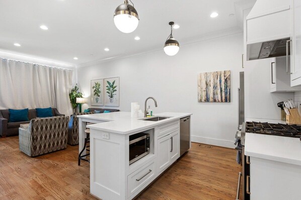 A modern kitchen with white cabinetry, a built-in oven, and a gas stove.