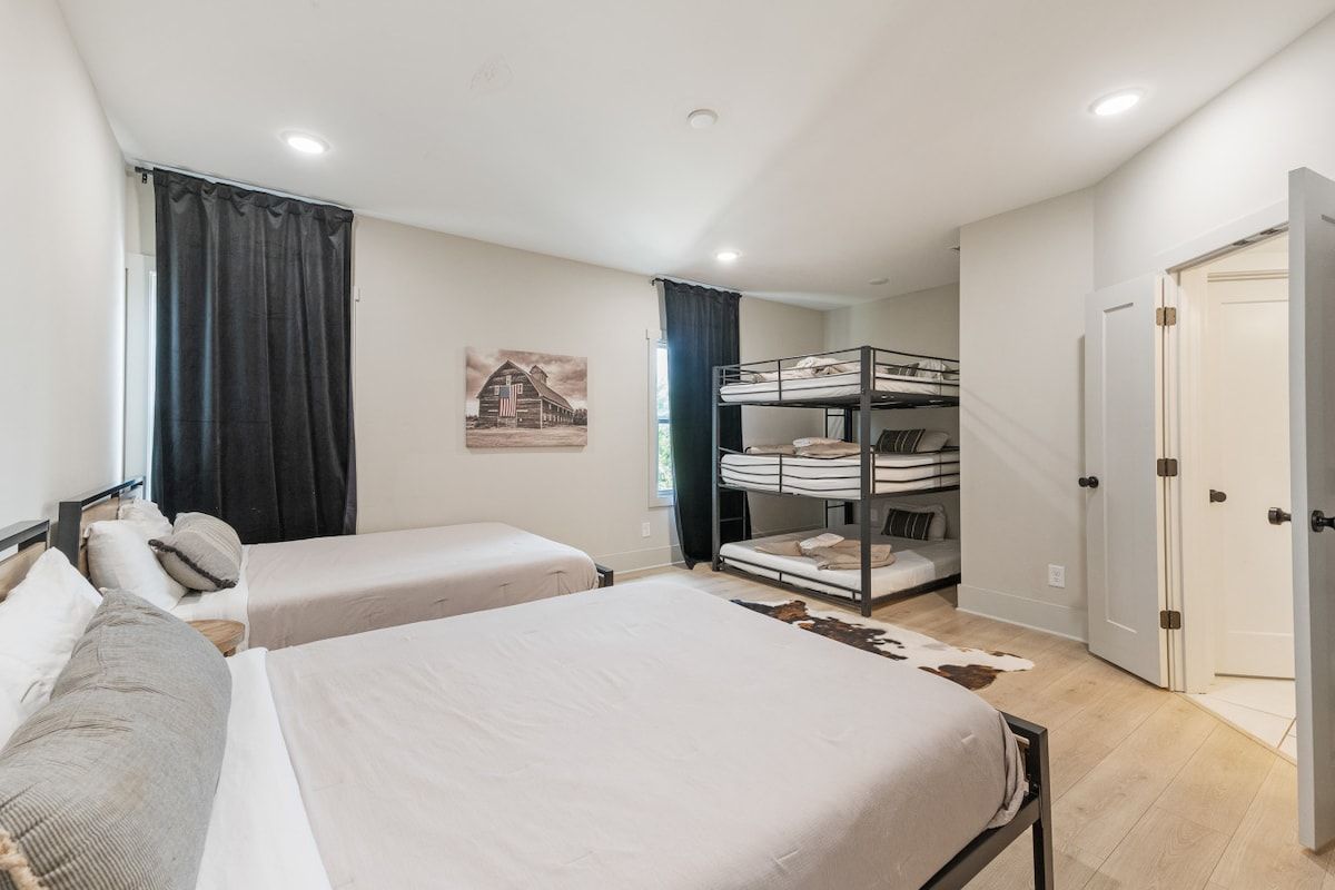Une chambre avec deux lits simples, un lit superposé, un tapis en peau de vache et une porte dotée d’une poignée.