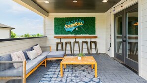 An outdoor patio with a sofa, a table, and a sign that reads 'Rock n Roll'.