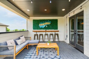 Une terrasse extérieure avec un canapé, une table et un panneau sur lequel on peut lire : « Rock n Roll ».