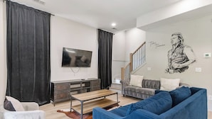 A living room with a TV, sofa, and a staircase.