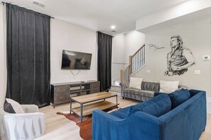 Un salon avec un téléviseur, un canapé et un escalier.