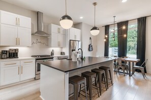 Une cuisine moderne avec des meubles blancs, des appareils en acier inoxydable et un îlot central doté de tabourets.