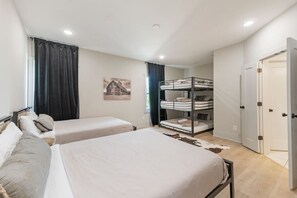 Quarto com duas camas de solteiro, uma cama beliche, um tapete de couro de vaca, um quadro com tema de fazenda e uma porta.