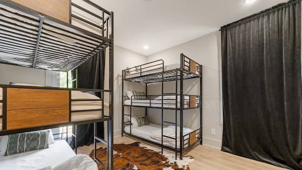 A bunk bed room with a cowhide rug, a curtain, and a ceiling with a slatted design.