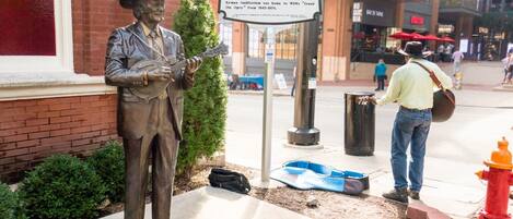 A statue of a man with a guitar, a sign with historical information, and a red fire hydrant.