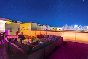 Un bar en la azotea con vistas a un horizonte urbano, zona de estar y barra.