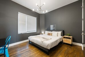 Un dormitorio con cama, mesita de noche y ventana con persianas.