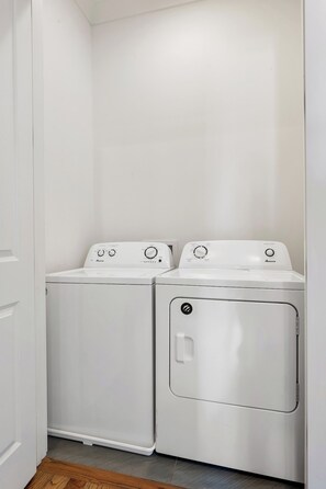 A laundry room with two white front-loading washing machines and a dryer.
