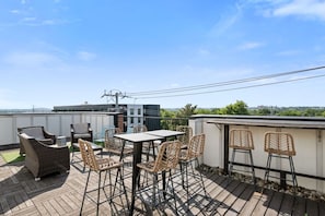A rooftop terrace with a table and chairs, a view of the city, and a clear sky.