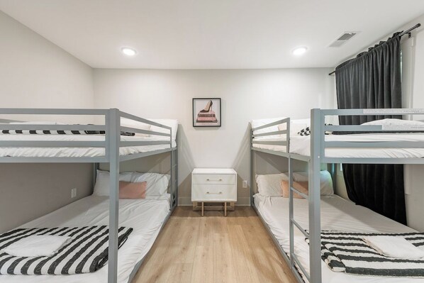 A room with bunk beds, a small white dresser, and a framed picture on the wall.