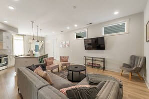 A modern living room with a sofa, chairs, a coffee table, and a TV mounted on the wall.