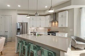 A modern kitchen with white cabinets, stainless steel appliances, and a central island with bar stools.
