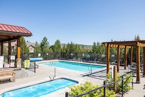 A swimming pool with lounge chairs and a gazebo, surrounded by a fence and trees. - Luxurious 3BR condo with mountain views, perfect for 6 guests. (Park City)