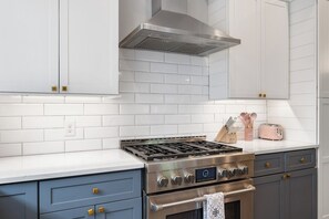 A modern kitchen with white tiled backsplash, stainless steel appliances, and blue cabinetry.