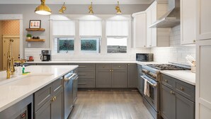 Une cuisine moderne avec des meubles gris, des plans de travail blancs et des appareils électroménagers en acier inoxydable.
