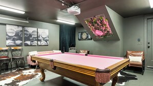 Une pièce équipée d’une table de billard, d’un jeu de fléchettes et d’un projecteur.