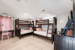 A room with bunk beds, a desk, and a chair.