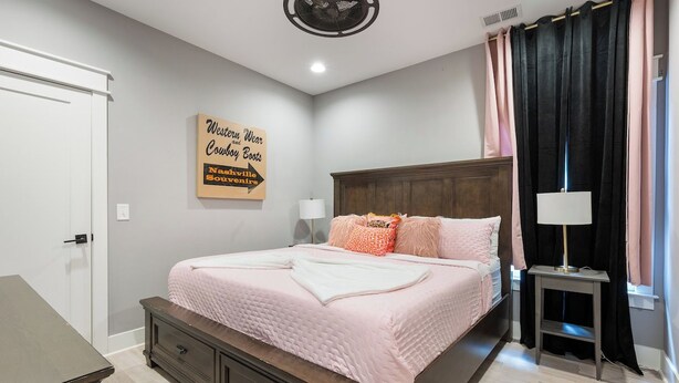 Une chambre à coucher avec un lit, une table de chevet, une lampe et un panneau décoratif au mur.