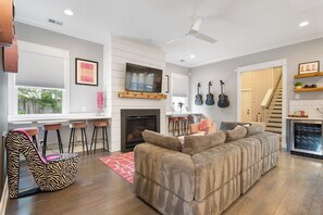 A modern living room with a sofa, a unique chair, a fireplace, and a television.