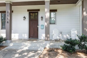 A white house with a dark brown front door, two lantern-style lights, and a mailbox.
