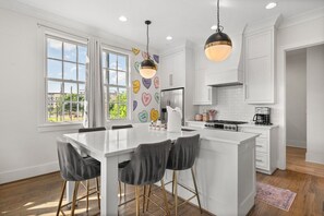 A modern kitchen with a central island, white cabinetry, and a view of the outdoors through large windows. - 21 Bed Downtown Luxury Bachelorette w Rooftop (Nashville)