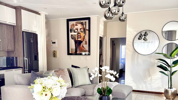 Ein modernes Wohnzimmer mit einem Glastisch, grauen Sofas und einem großen abstrakten Gemälde.
