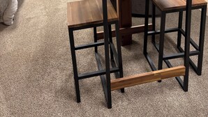 Une pièce avec une table en bois, deux chaises, un lit et un téléviseur fixé au mur.
