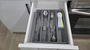A kitchen drawer with utensils and a stove.