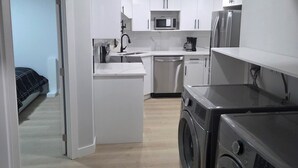 A compact kitchen with a microwave, refrigerator, sink, and washing machine.