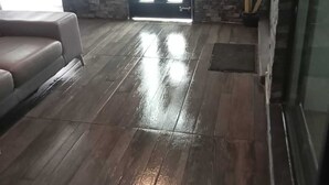 Una habitación con piso de madera, un sofá, una puerta con paneles de vidrio y una planta en maceta.