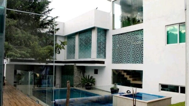 Un edificio moderno con fachada de vidrio, piscina y escalera.