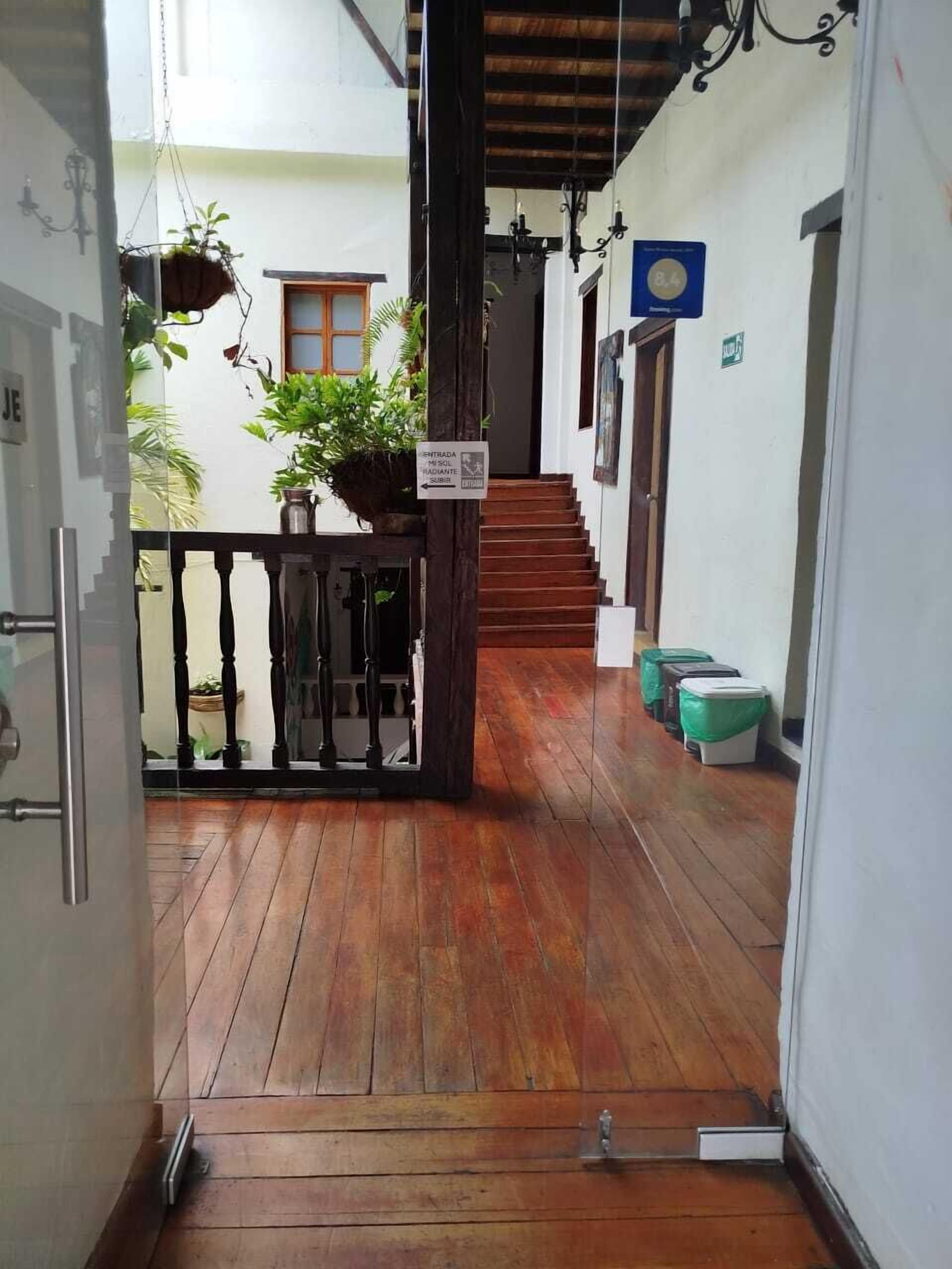 A wooden-floored corridor with a staircase leading to an upper level, potted plants, and a sign indicating a smoking area.