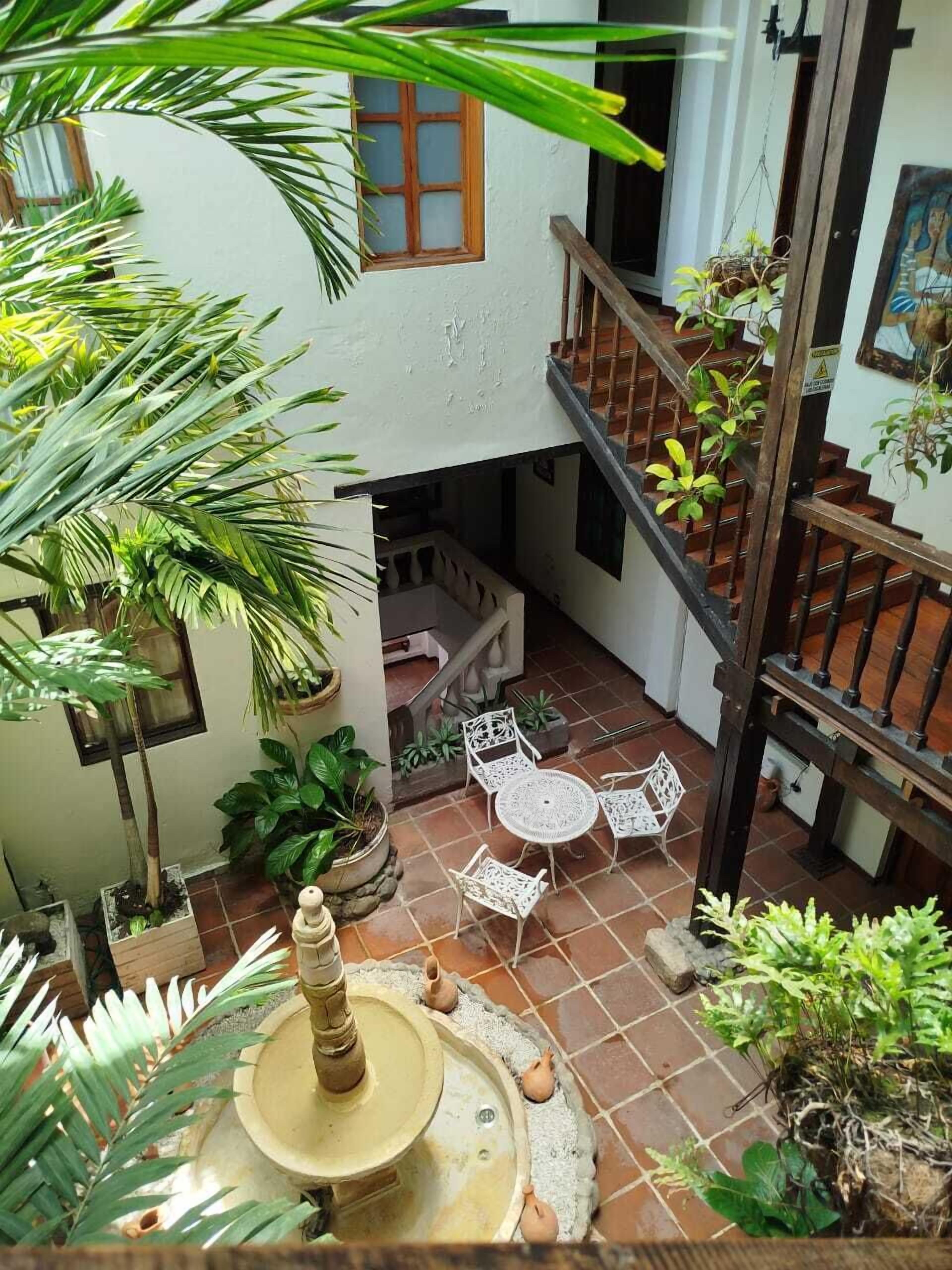 A courtyard with a fountain, potted plants, a staircase, and outdoor seating.