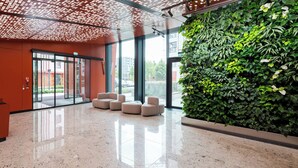 A modern lobby with a glass wall, a green vertical garden, and a polished marble floor.