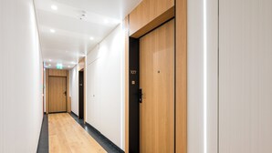 A hallway with wooden doors, numbered 107 and 108, and a black carpeted floor.