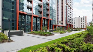 A modern building with multiple floors, large windows, and a landscaped courtyard with greenery. - Towarowa Towers 106 Superior Studio (Warszawa)