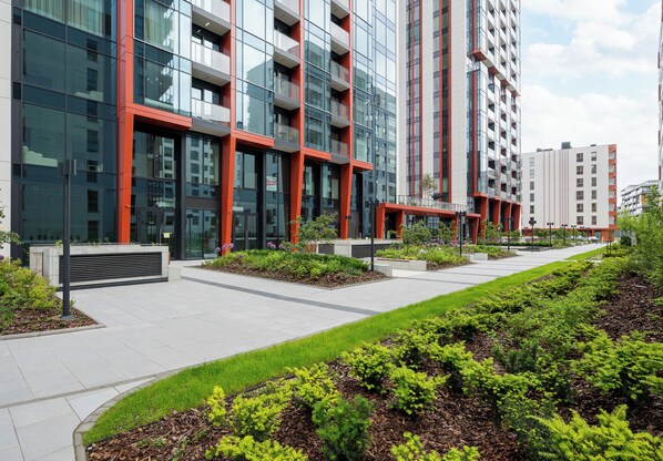 A modern building with multiple floors, large windows, and a landscaped courtyard with greenery.