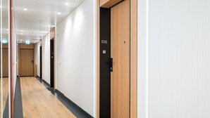 A modern hallway with wooden doors numbered 106 and 107, leading to rooms. - Towarowa Towers 106 Superior Studio (Warszawa)