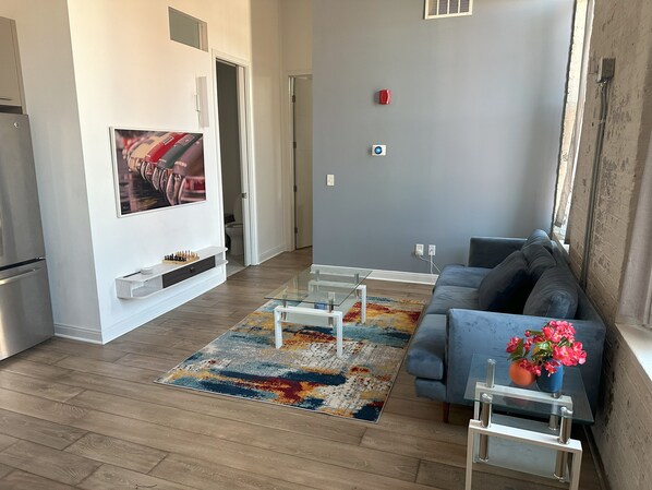 A spacious living area with a modern sofa, a glass coffee table, and a colorful rug.