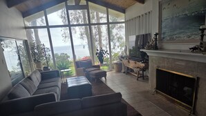 Una sala de estar con un ventanal grande, chimenea y sofá.