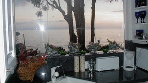 Cocina con vistas al mar, que incluye un lavamanos, un tostador y objetos decorativos en la encimera.
