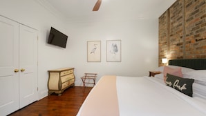 Ein Schlafzimmer mit einem großen Bett, einem Schminktisch, einem Fernseher und Bildern an der Wand.